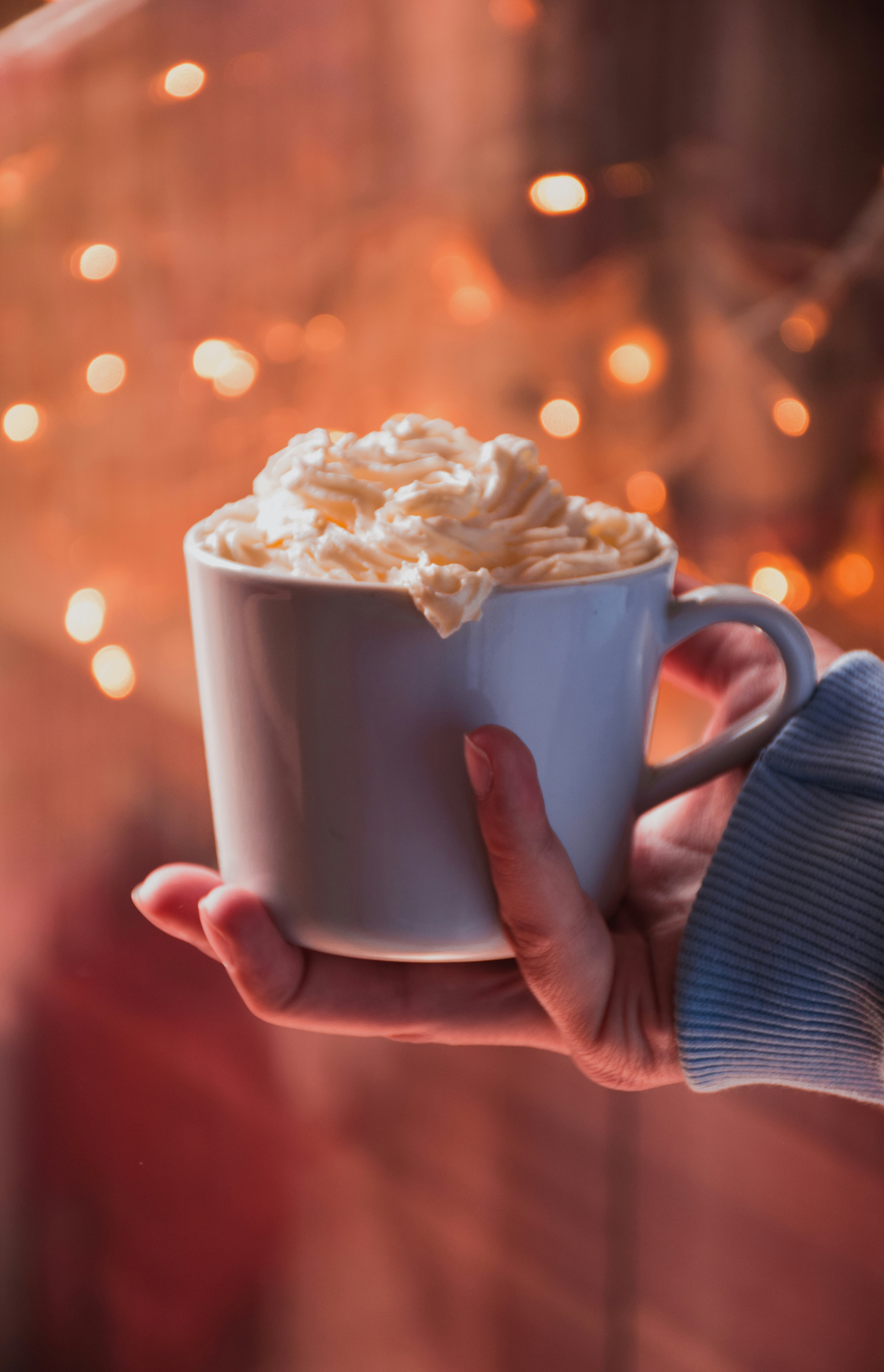 person holding white ceramic mug with white cream